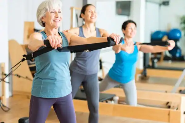 Toning Arms After 60: Empowering Womens Fitness Through Effective Weight Training 2 older woman doing weight training West Bridgford and resistance in the gym to tone upper arms