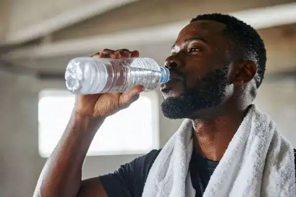 Image of man drinking water to improve hydration West Bridgford after work out.